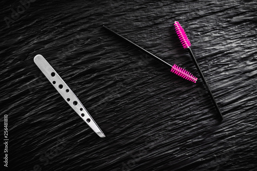 on the black background lies a pair of tweezers and eyebrow comb brush the top view copy space photo