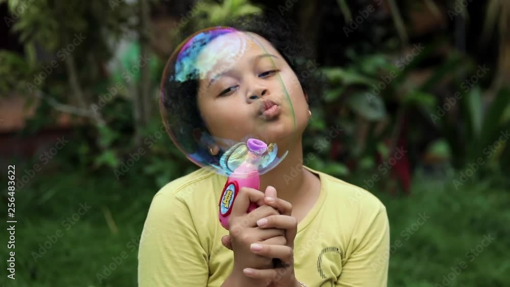 Unhappy kid elementary age with her boring toy, playing colourful bubble. Unhappy kid elementary age with her boring toy, playing colourful bubble.