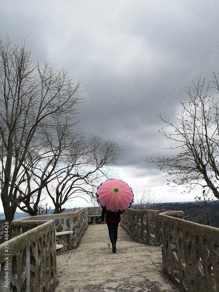 girl walks under umbrella in the park