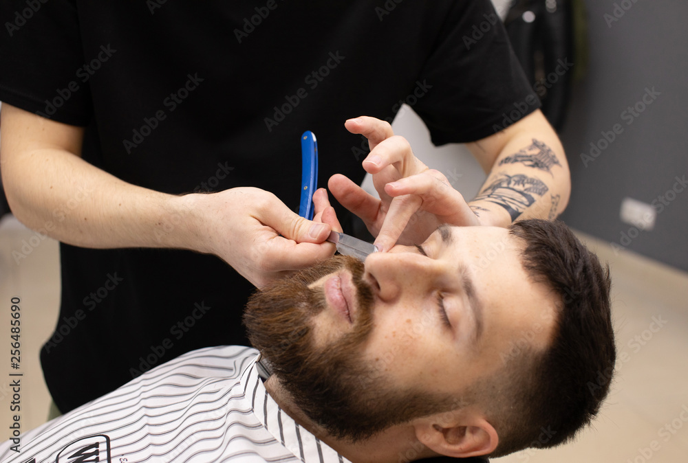Fototapeta premium Client during beard shaving in barber shop