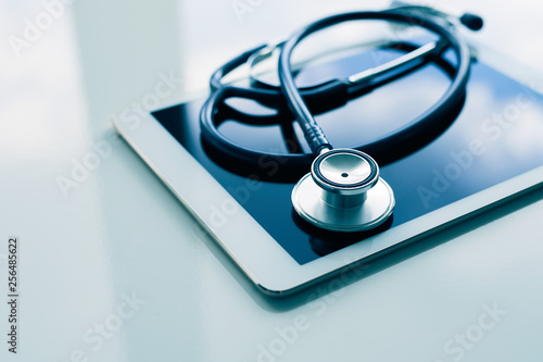 Medical equipment on table. Blue stethoscope and tablet on white background. 