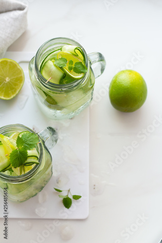 glasses with water, mint, lime and cucumber on a white board top wive