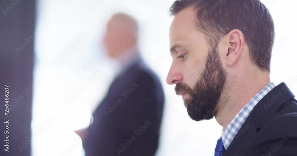 4K Closeup businessman working at his desk with colleagues blurred in background. Slow motion. 4K Closeup businessman working at his desk with colleagues blurred in background. Slow motion.