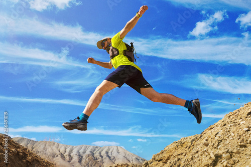 Athlete runs off-road. Jumps over a ravine. Trail runner in the desert