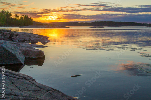 Rocky coast of the island. Sunrise in the wild. Sunrise Sun over the lake. Stones in the water. Islands in Lake Ladoga. Karelia. The nature of Russia. Ladoga lake. © Grispb