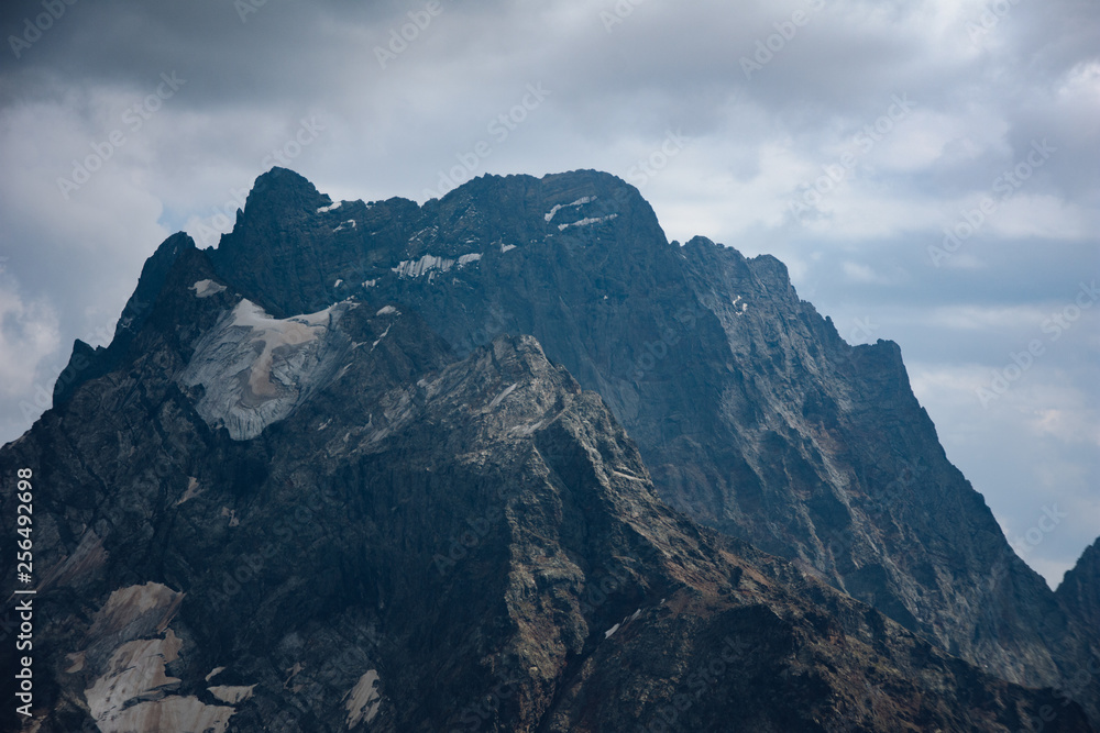 Obraz premium The peaks of the Caucasus Mountains in cloudy clouds and the rays of the sun through them in the outskirts of Dombai. And on the tops of snow lies.