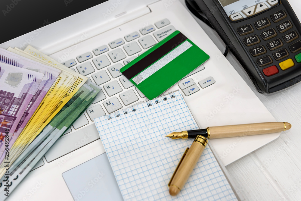 Obraz premium Euro banknotes on laptop and banking terminal