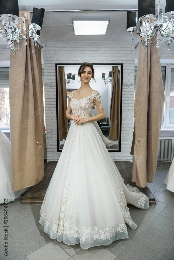 Fototapeta premium Bride in wedding dress posing with hands on waist