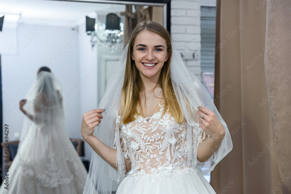 Beautiful bride in wedding dress posing before mirror Beautiful bride in wedding dress posing before mirror