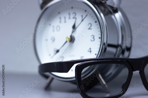 Alarm clock and glasses on the shelf