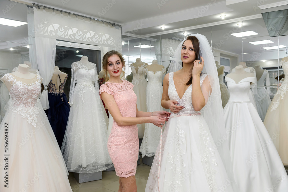 Saleswoman in wedding salon helping to young bride Saleswoman in wedding salon helping to young bride