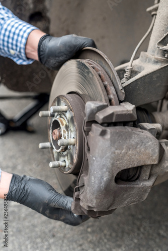 Hands of mechanic repairing brake disk of a car