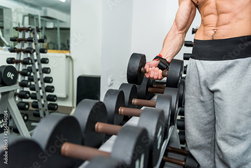 Male hands with dumbbells in gym closeup