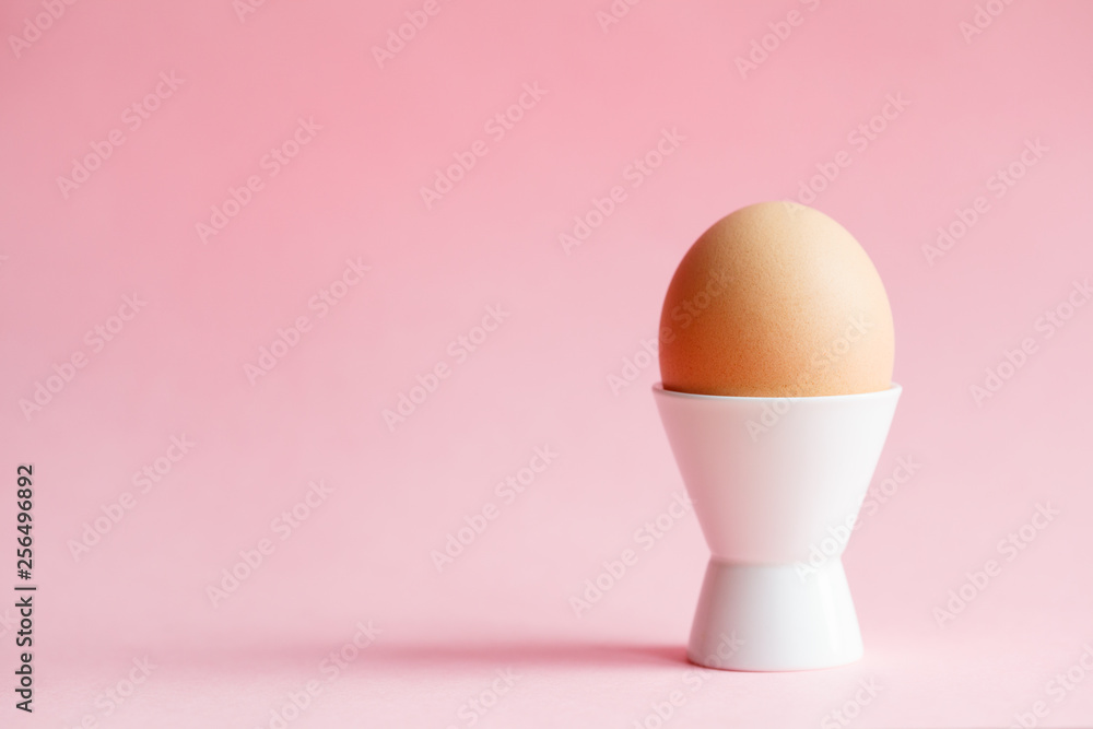 chicken egg in eggcup isolated on pastel pink background chicken egg in eggcup isolated on pastel pink background