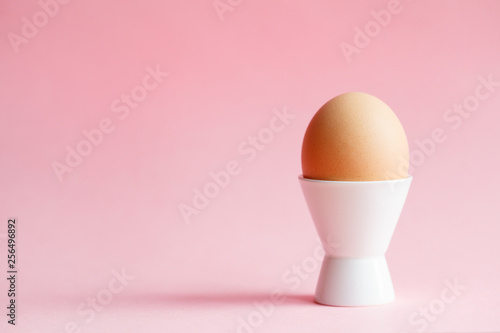 chicken egg in eggcup isolated on pastel pink background photo
