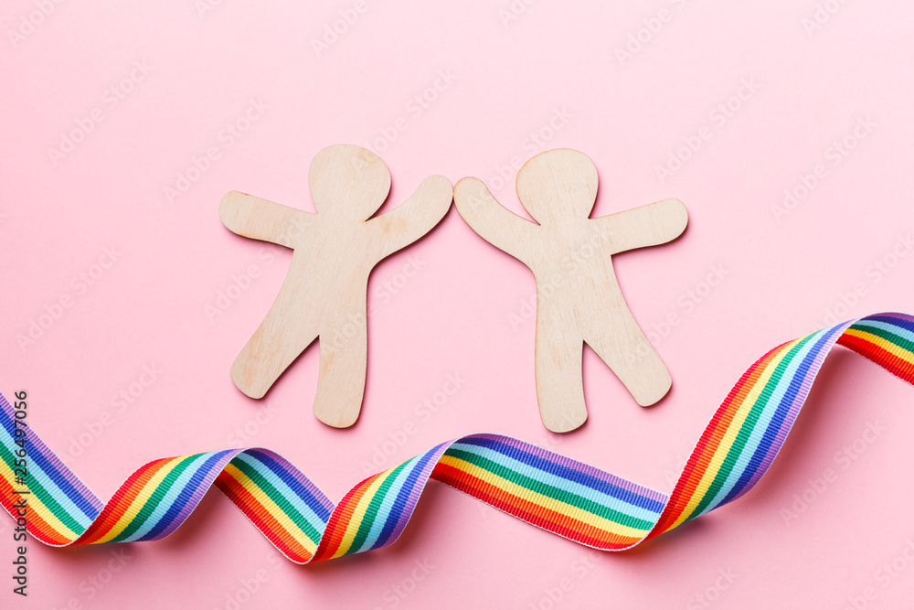 LGBT rainbow ribbon and wooden people silhouettes isolated on pink background, flat lay, top view, gay pride concept LGBT rainbow ribbon and wooden people silhouettes isolated on pink background, flat lay, top view, gay pride concept