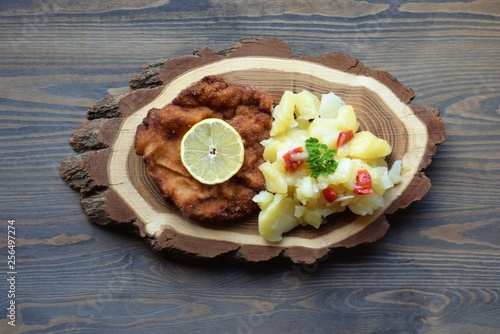 Weiner schnitzel with potato salad on a wooden background