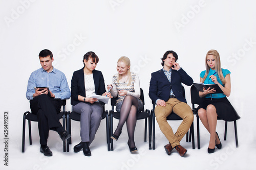 business people waiting in queue sitting in row holding smartphones and cvs, human resources, employment and hiring concept