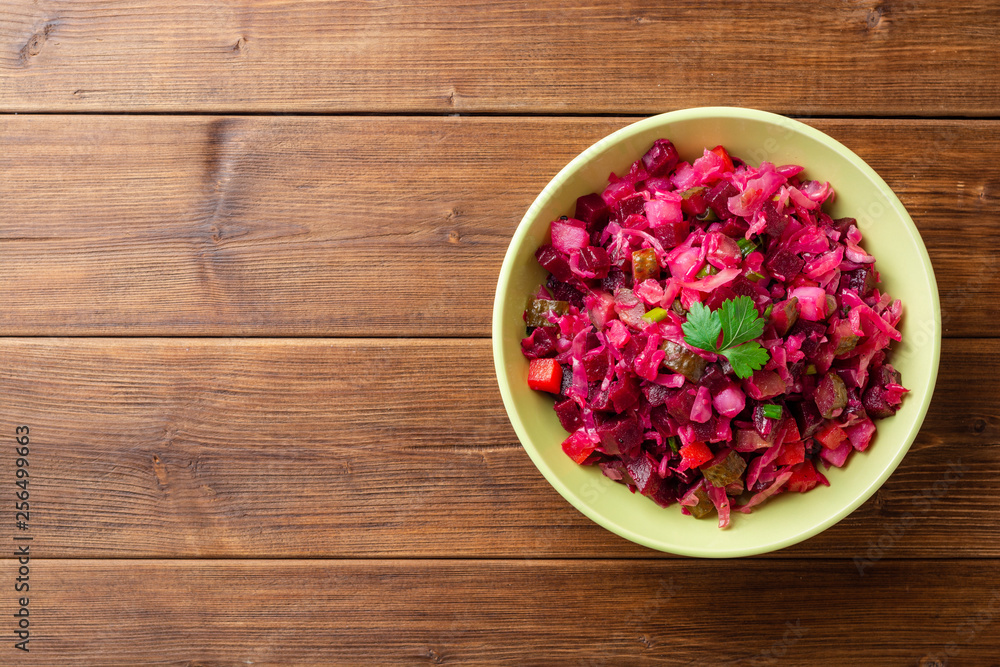 Traditional russian salad vinaigrette with boiled vegetables, pickled cucumbers and sauerkraut in bowl on wooden table. Top view. Copy space. Traditional russian salad vinaigrette with boiled vegetables, pickled cucumbers and sauerkraut in bowl on wooden table. Top view. Copy space.