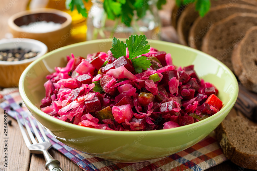Traditional russian salad vinaigrette with boiled vegetables, pickled cucumbers and sauerkraut in bowl on wooden table. Selective focus. Traditional russian salad vinaigrette with boiled vegetables, pickled cucumbers and sauerkraut in bowl on wooden table. Selective focus.