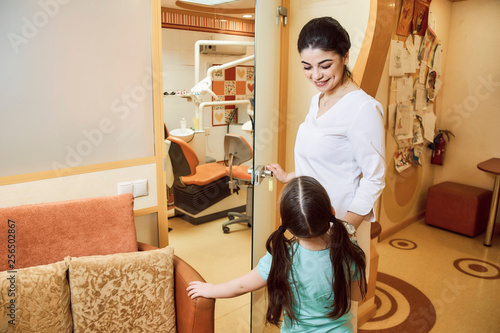 Pediatric dentistry. The dentist invites the girl to the office