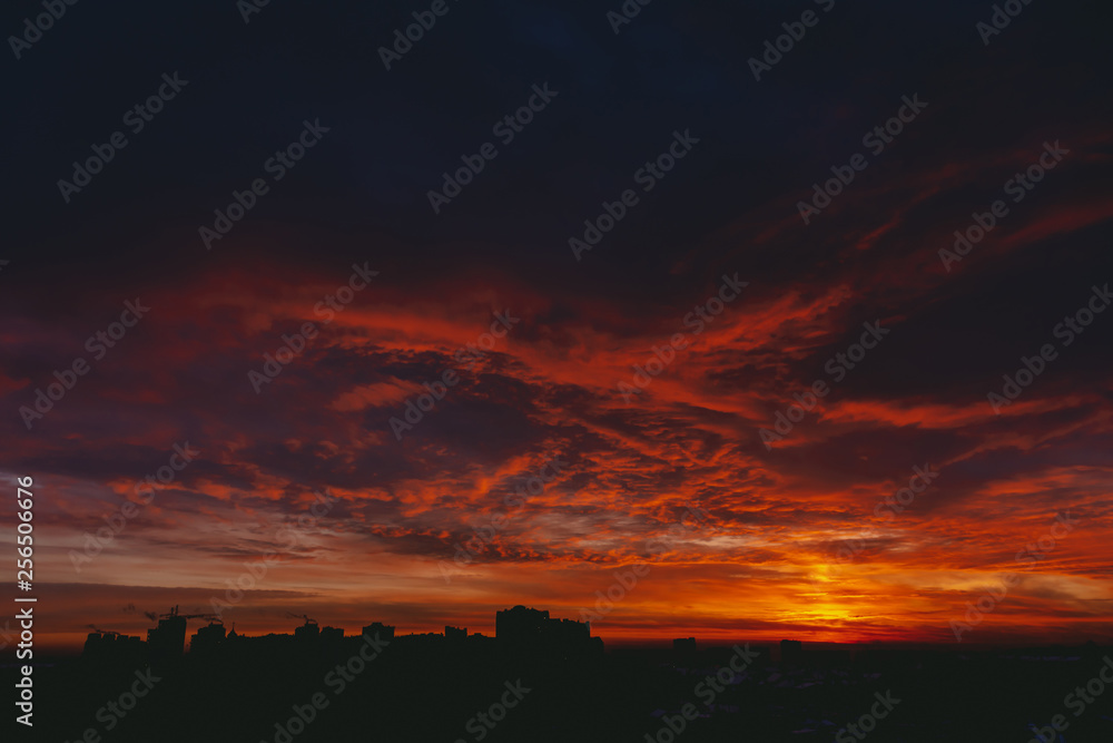 Obraz premium Fiery red blood vampire dawn. Amazing warm dramatic fire blue dark cloudy sky. Orange sunlight. Atmospheric background of sunrise in overcast weather. Hard cloudiness. Storm clouds warning. Copy space