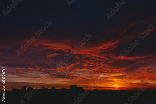 Fiery red blood vampire dawn. Amazing warm dramatic fire blue dark cloudy sky. Orange sunlight. Atmospheric background of sunrise in overcast weather. Hard cloudiness. Storm clouds warning. Copy space