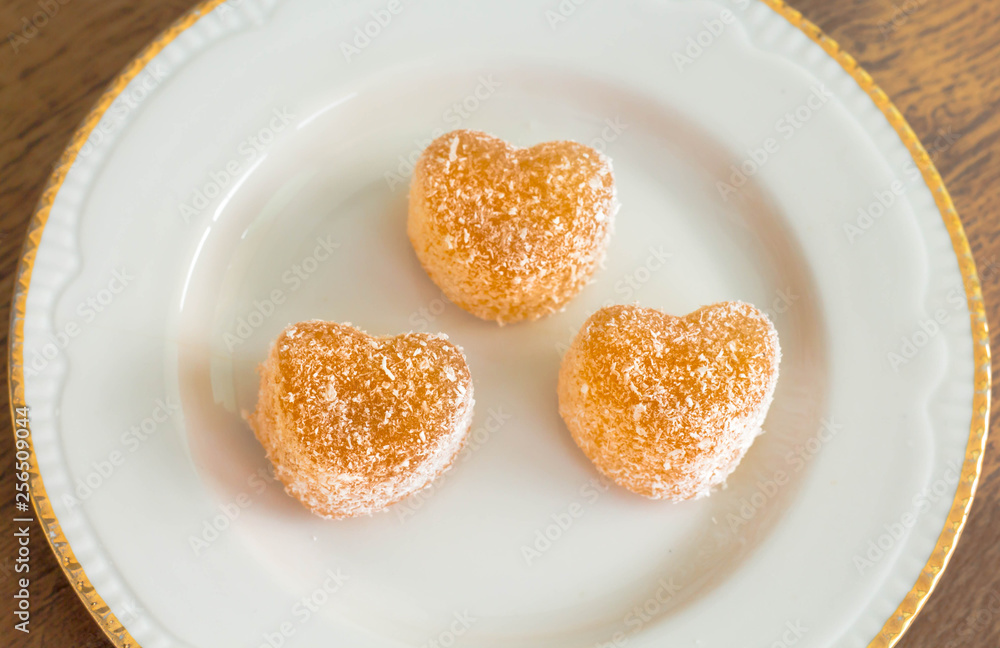 three small heart shaped candied fruit jelly sprinkled with coconut chips, healthy food, vegan three small heart shaped candied fruit jelly sprinkled with coconut chips, healthy food, vegan