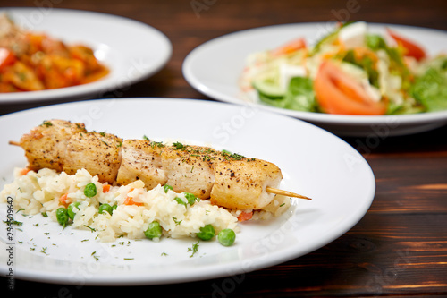 chicken kebab with rice and vegetables on the wooden background
