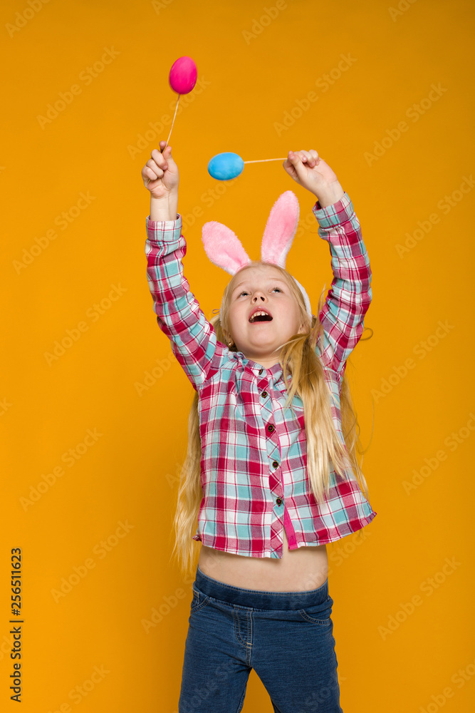 Portrait of cute little child girl with Easter bunny ears holding colorful eggs on yellow background. Happy easter Portrait of cute little child girl with Easter bunny ears holding colorful eggs on yellow background. Happy easter