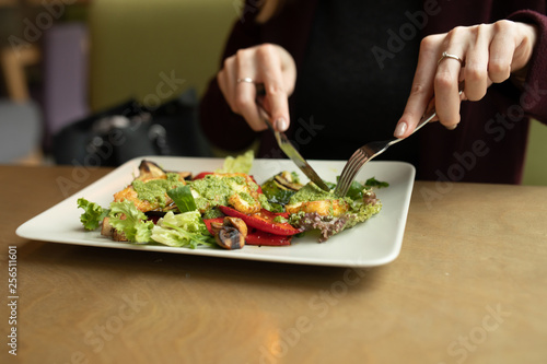 Close up attractive woman hand holding fork and spoon to eating vegetable salad at lunch in cafe 