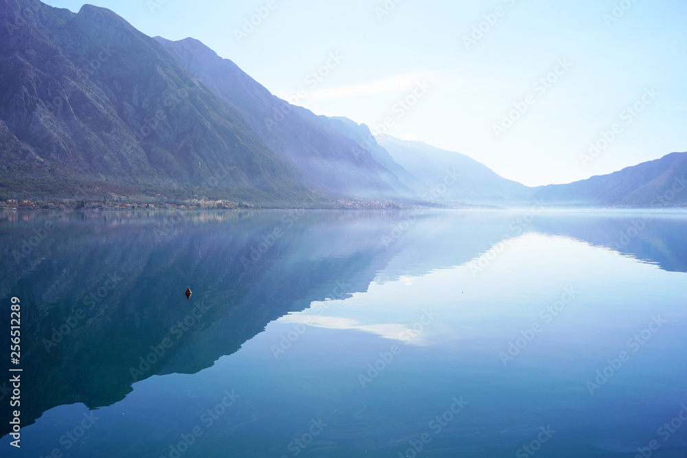 Fototapeta premium Morning in Boka Bay, Montenegro: high mountains and their reflection in calm sea water.