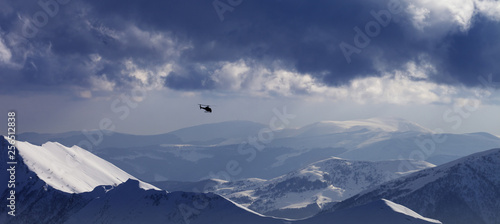 Off-piste slope for heliskiing and helicopter in evening mountains