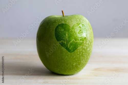 a green apple with a heart and an electrocardiogram wave shape over