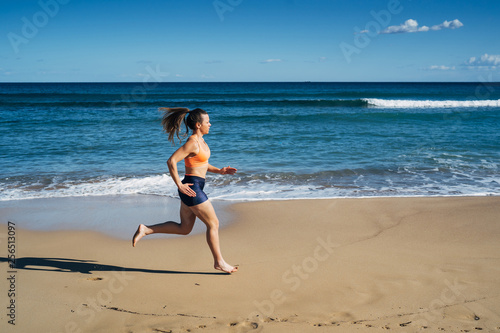 Fitness young woman running on the beach during summer holiday © ManuPadilla