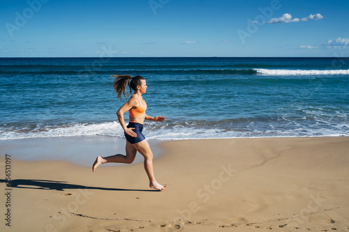 Fitness young woman running on the beach during summer holiday