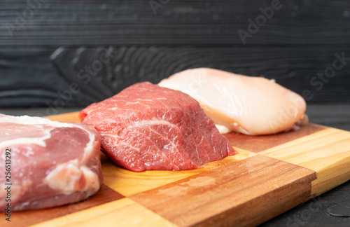Various fresh raw meats on wooden background. 
