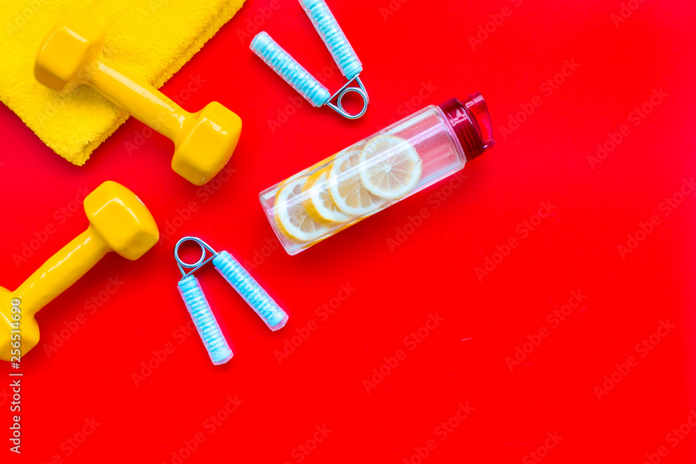Sport with bars, towel, water and wrist builder red background top view space for text Sport with bars, towel, water and wrist builder red background top view space for text