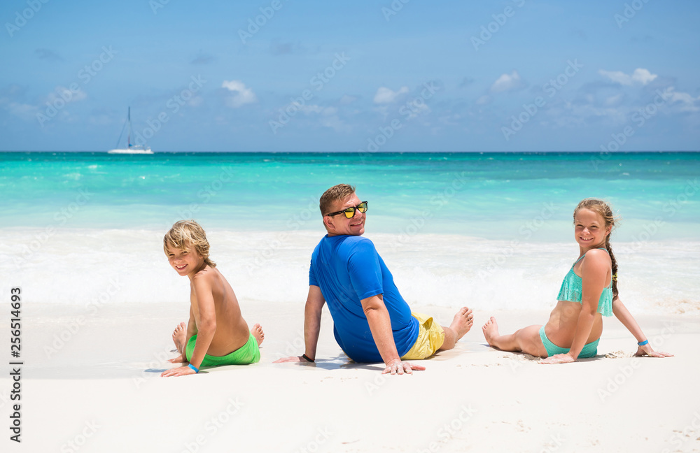 Happy family at the tropical beach during  summer vacation	. Smiling Father with children .
