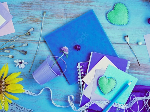  Seasonal summer composition of a pair of felt hearts, paper with a pencil, notebooks and decor on a blue table, top view, concept of writing a plan for preparing for a romantic trip, relaxation, vint photo