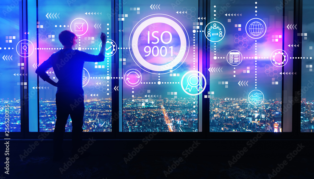 Obraz premium ISO 9001 with man writing on large windows high above a sprawling city at night