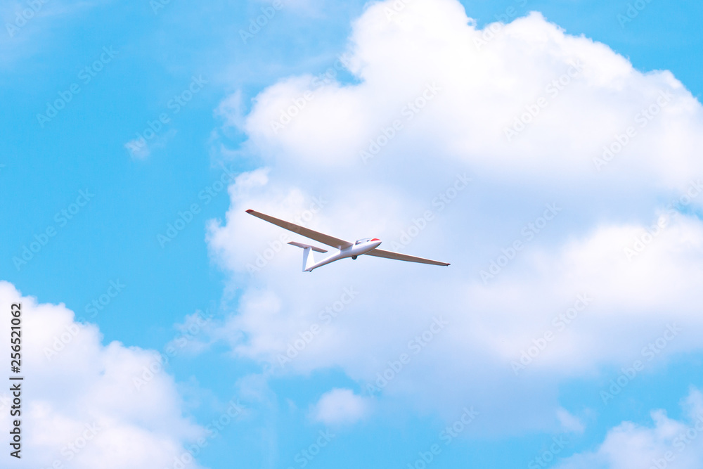 Obraz premium Small glider flying against the blue sky and clouds