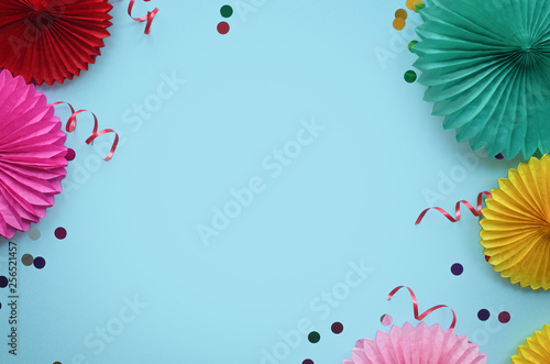 Paper texture flowers with confetti on blue background. Birthday  holiday or party background. Flat lay style.