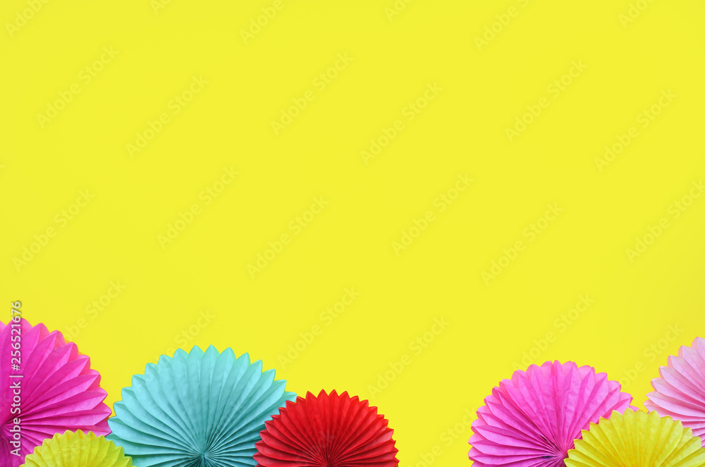 Paper flowers on yellow table top view. Festive or party background. Flat lay style. Copy space for text. Birthday greeting card.