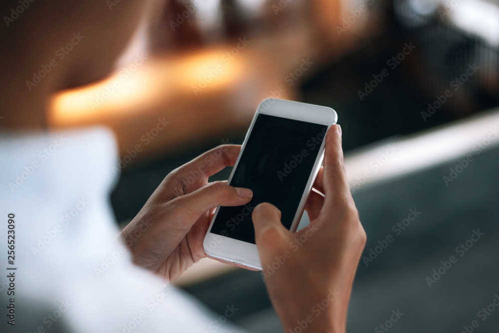 Woman using a smartphone read and text messages with blank space screen display from behind view- woman office worker- digital and communication concept