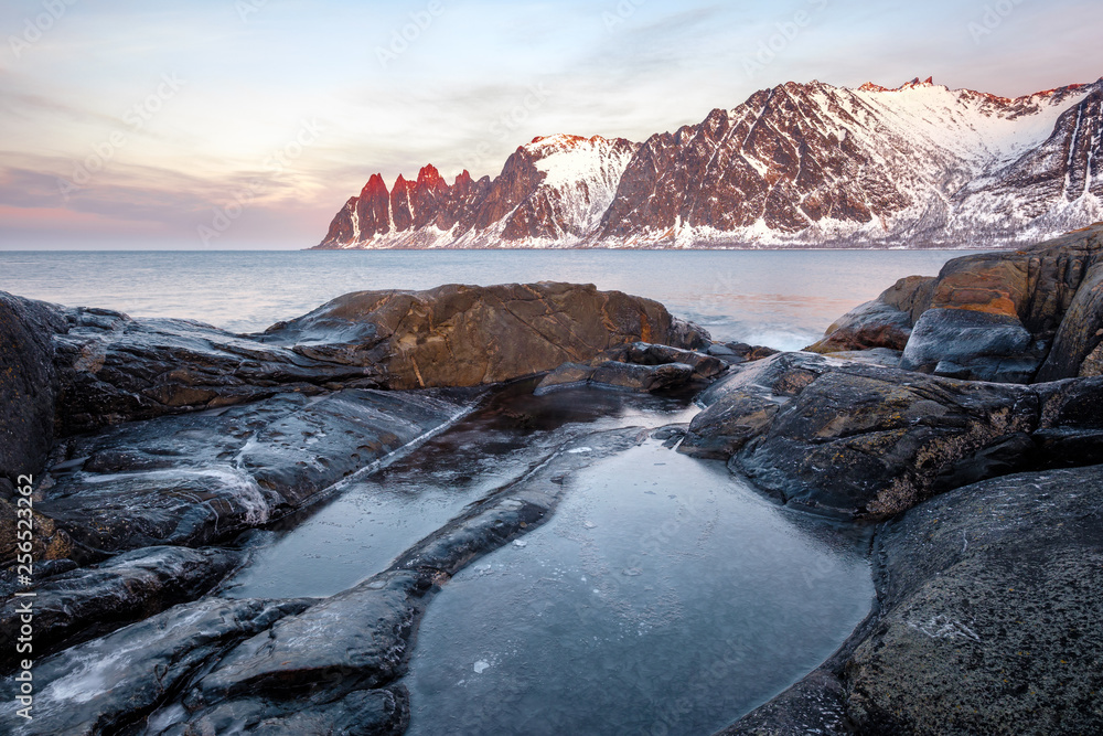 View over rocks and rockpools to snowy Oksen mountains, Tungeneset Senja Norway