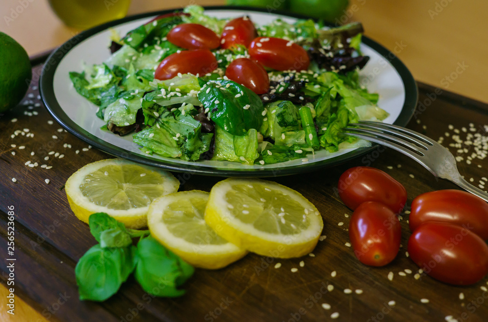 Fresh salad from different kinds of greens and a cherry tomato, dressed with olive oil and sprinkled with sesame seeds. Fresh salad from different kinds of greens and a cherry tomato, dressed with olive oil and sprinkled with sesame seeds.