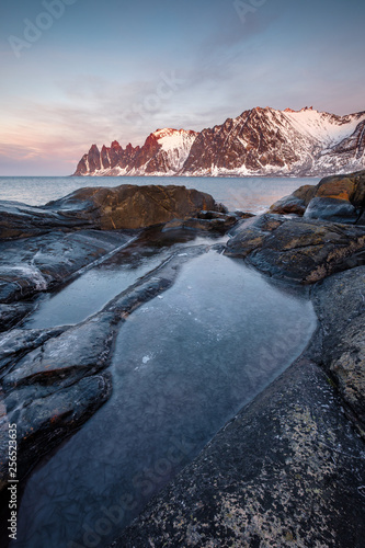 Frozen Rockpool in front of snowy mountains and sea, Oksen Tungeneset Senja, Norway