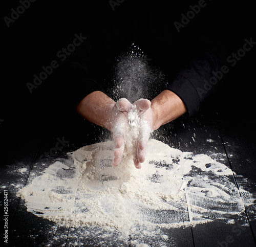 man s hands and splash of white wheat flour