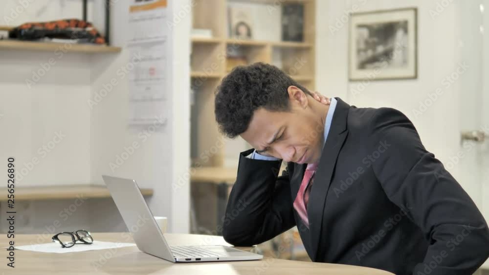 Tired African Businessman with Neck Pain working on Laptop Tired African Businessman with Neck Pain working on Laptop